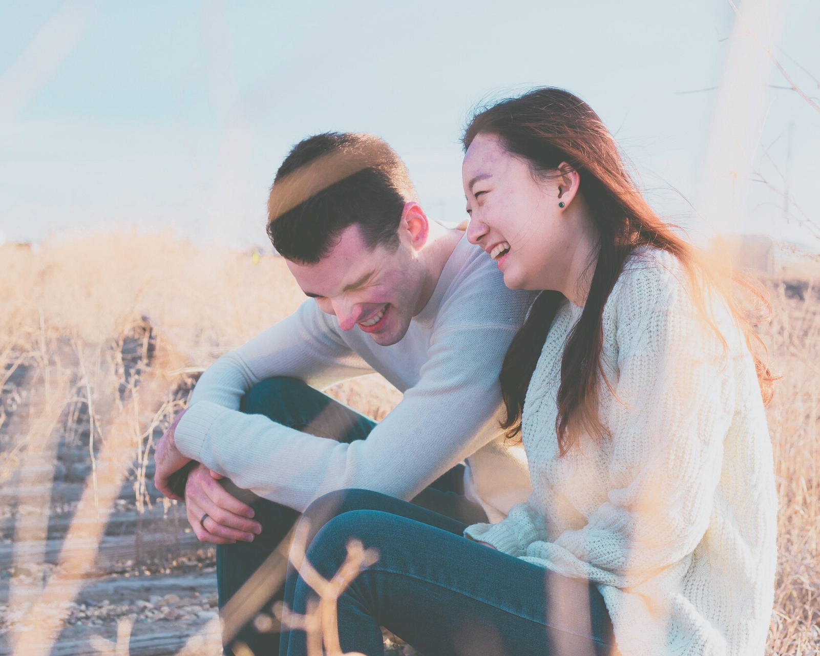 Smiling couple sitting outdoors in a sunlit field, sharing a joyful moment—symbolizing emotional renewal, connection, and the life-changing impact of ketamine and SPRAVATO therapy at Mind Rejuvenation, Tulsa’s trusted mental wellness clinic.