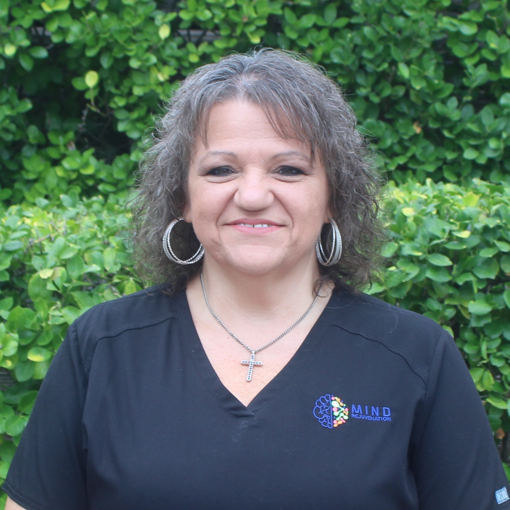 Peggy Shearl, Office Manager, Billing Specialist, and Prior Authorization Coordinator at Mind Rejuvenation, smiling in branded attire outdoors. Featured on the Meet Our Team page to reflect dedication, warmth, and behind-the-scenes expertise in patient care.